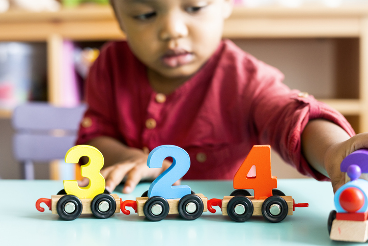 Little boy playing with a wooden number toy at nursery